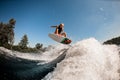 Active energetic man on surf style wakeboard masterfully jumping over splashing wave Royalty Free Stock Photo