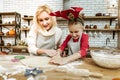 Active expressive child cutting spread dough with special tool