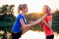 Active family at outdoor. two flexibility blonde twin sisters in stylish sportswear warm-up stretching full split twine