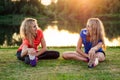 Active family at outdoor. two flexibility curly blonde woman twin sisters in stylish sportswear warm-up stretching full