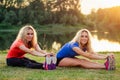 Active family at outdoor. two flexibility curly blonde woman twin sisters in stylish sportswear warm-up stretching full