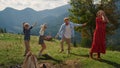 Active family playing dancing on green hill. Joyful father jumping with children Royalty Free Stock Photo