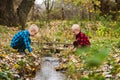 Curious twin brothers sit near water stream