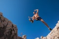 Active fast running mountain sky runner smiling and jumping over the cleft cliff during the high morning enduro race. Sporty Royalty Free Stock Photo