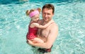 Active father teaching his child girl to swim in pool .