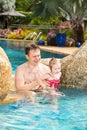 Active father teaching his toddler daughter to swim in pool on tropical resort Royalty Free Stock Photo