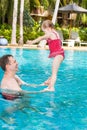 Active father teaching his toddler daughter to swim in pool on tropical resort. Royalty Free Stock Photo