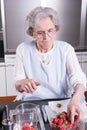 Active female pensioner is preparing strawberries in the kitchen Royalty Free Stock Photo