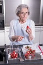 Active female pensioner is preparing strawberries in the kitchen Royalty Free Stock Photo