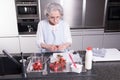 Active female pensioner is preparing strawberries in the kitchen Royalty Free Stock Photo