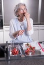 Active female pensioner is preparing strawberries in the kitchen Royalty Free Stock Photo