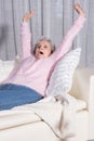 Active female senior stretching on couch