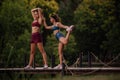 Active females warming up in park. Fit girls stretching on bridge. Athletic bodies exercising outdoors. Muscular women