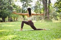 Active Asian woman training in the green park, doing Crescent Lunge Twist on the knee pose