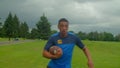 Active fit black American football player with ball passing by defender on field