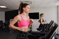 Active fit brunette woman smiling, pink top, running on gym treadmill