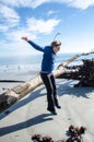 Active fit woman jumps off a large piece of driftwood on the beach of Hunting Island State Park Royalty Free Stock Photo