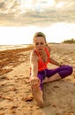 Active fit woman in sports gear on seacoast stretching