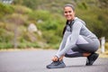 Active and fit woman tying the laces of her sneakers for exercise outdoors. Athlete fixing her shoes to get ready for a Royalty Free Stock Photo