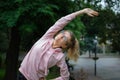 Active fitness woman in pink clothes and eyeglasses is stretching outdoor in the park during spring or summer morning Royalty Free Stock Photo