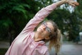 Active fitness woman in pink clothes and eyeglasses is stretching outdoor in the park during spring or summer morning Royalty Free Stock Photo