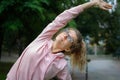 Active fitness woman in pink clothes and eyeglasses is stretching outdoor in the park during spring or summer morning Royalty Free Stock Photo