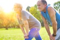 Active flexible senior couple stretching leg in park on sunny day