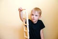 Active funny kid boy is building a structure from nature wooden building blocks.