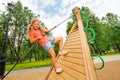 Active girl climbs on wooden construction