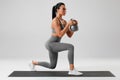 Active girl doing lunges exercises with kettlebell, leg muscle training. Fitness woman doing front forward one leg step lunge