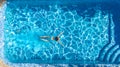 Active girl in swimming pool aerial drone view from above, young woman swims in blue water, tropical vacation