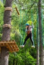 Active girl walking on suspended ropes in forest