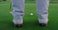 Active golfer swing club on golf course. Man legs stand on green grass fairway.