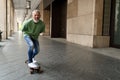 Active happy cool older man skater riding skateboard in the city street.