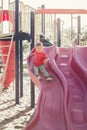 Active happy funny smiling Caucasian boy child sliding on playground schoolyard outdoors on summer sunny day. Kid having fun. Royalty Free Stock Photo