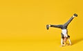 Active happy girl child upside down on yellow background