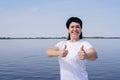 Active and happy senior woman in sportswear showing thumbs up working out near the riverside Royalty Free Stock Photo