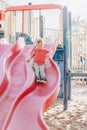 Active happy smiling Caucasian boy sliding on playground. Kid on schoolyard outdoors on summer sunny day. Child having fun outside Royalty Free Stock Photo