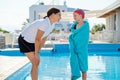 Active healthy lifestyle in children. Woman trainer talking to girl child near outdoor pool Royalty Free Stock Photo