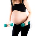 Active healthy pregnant woman exercising with dumbells, isolated on white background