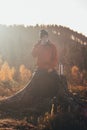 Active hiker sitting on a fire drinking hot tea to warm up at sunrise. A hiker is enlightened by the morning sun and enjoys the