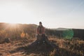 Active hiker sitting on a stump enjoys the feeling of reaching the top of the mountain at sunrise. A hiker is enlightened by the