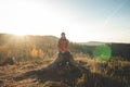 Active hiker sitting on a stump enjoys the feeling of reaching the top of the mountain at sunrise. A hiker is enlightened by the Royalty Free Stock Photo