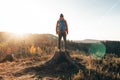 Active hiker standing on a stump enjoys the feeling of reaching the top of the mountain at sunrise. A hiker is enlightened by the