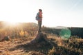 Active hiker standing on a stump enjoys the feeling of reaching the top of the mountain at sunrise. A hiker is enlightened by the