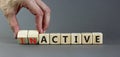 Active or inactive symbol. Businessman turns wooden cubes and changes the word Inactive to Active. Beautiful grey table grey