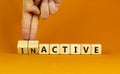 Active or inactive symbol. Businessman turns wooden cubes and changes the word Inactive to Active. Beautiful orange table orange