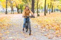 An active joyful girl enjoys cycling in a city autumn park.