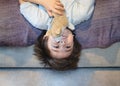 Active kid laying upside down watching TV on the sofa, Happy Child playing with dog toy, Cute boy is lying his backs on couch and Royalty Free Stock Photo