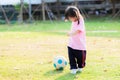 Active kid playing blue-white soccer ball. Girl was happy to play sports to exercise and strengthen her body.